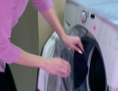 machine washable - person putting mask in washing machine 
