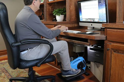 Man pedaling on Blu Tiger while sitting down and working in home office